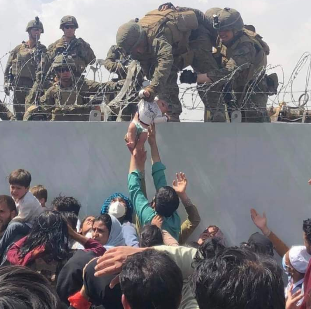 صادم لقطة حزيتة ومأساوية لأم  أفغانية تسلم طفلها الرضيع لجنود أمريكيين عبر الأسلاك الشائكة بمطار كابل في رحلة الهروب من أفغانستان